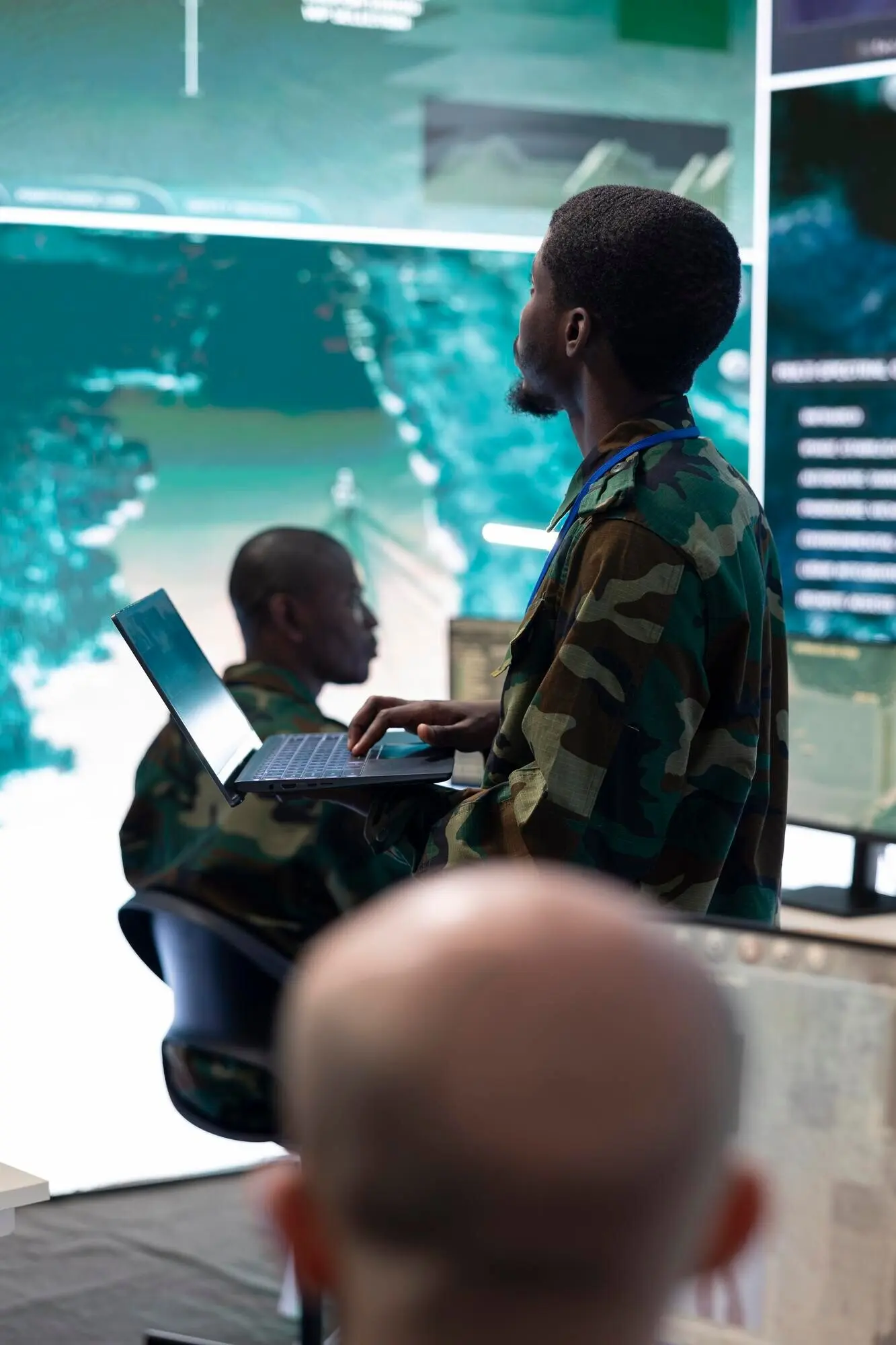 Militärrekrut sichtet Aufnahmen der Radarüberwachung auf einem großen Bildschirm.